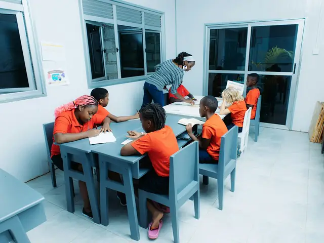 A teacher helping a group of children working at their tables