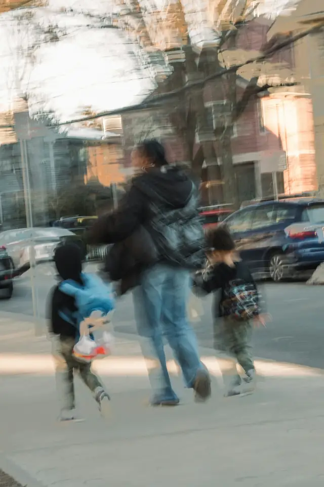 A parent walking two children along the pavement